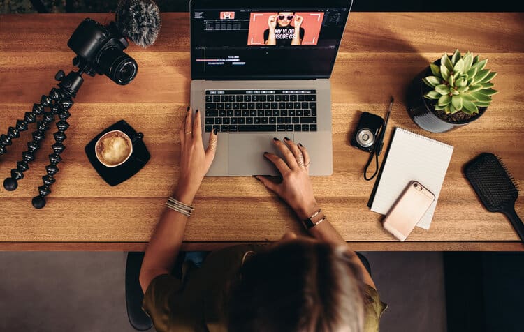 Young female vlogger editing her vlog on computer.